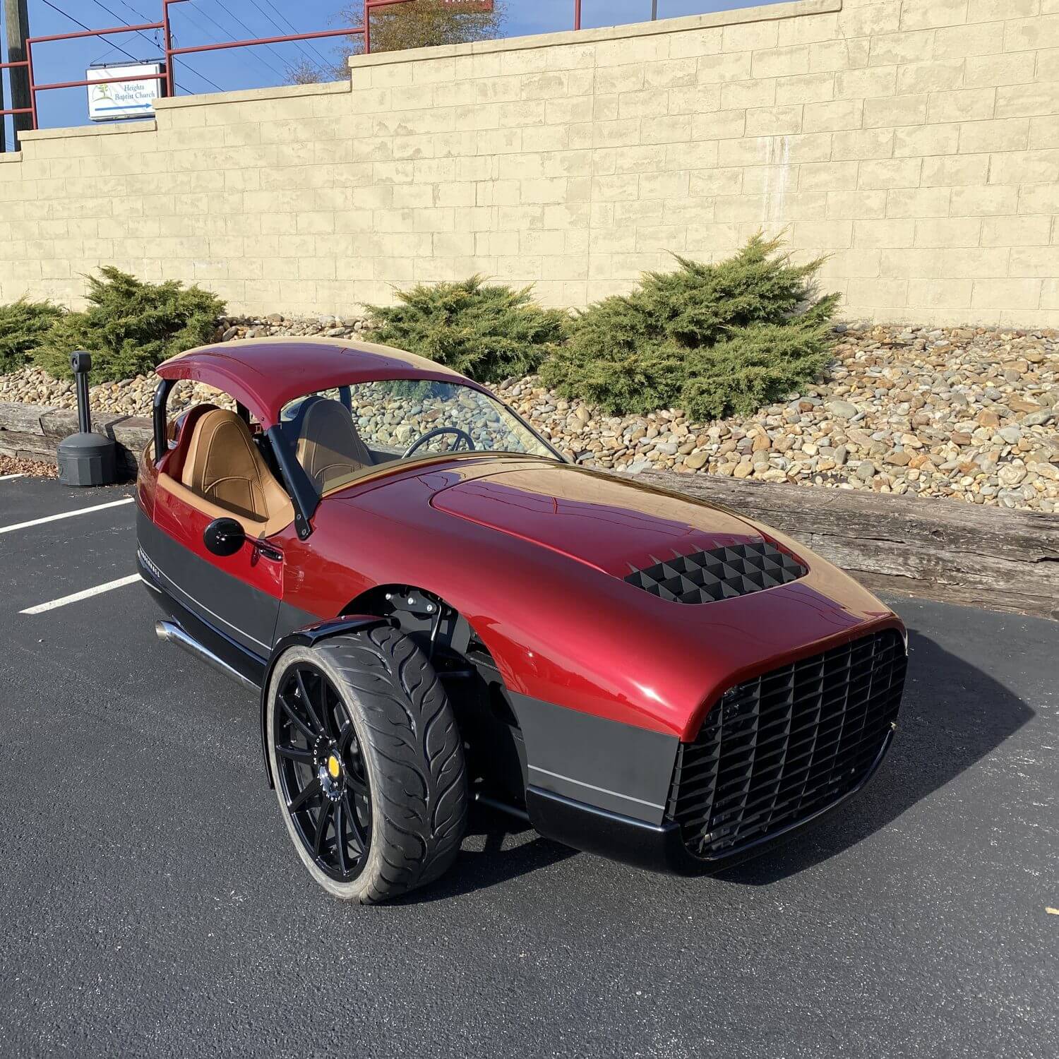 Red three wheel Vanderhall showcased in parking lot of rental agency