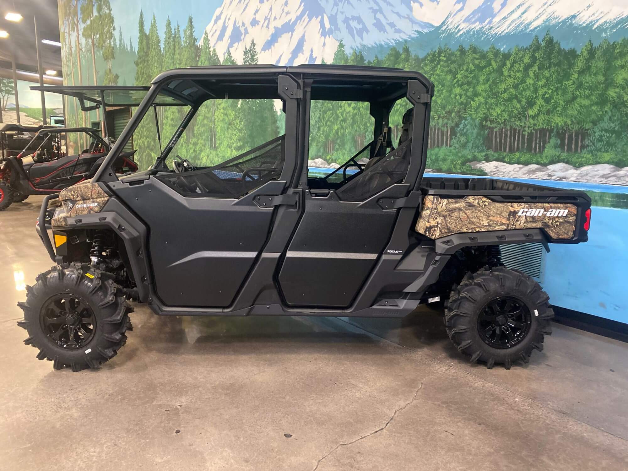 Defender Six Seater UTV showcased in dealership with a mountain forest backdrop